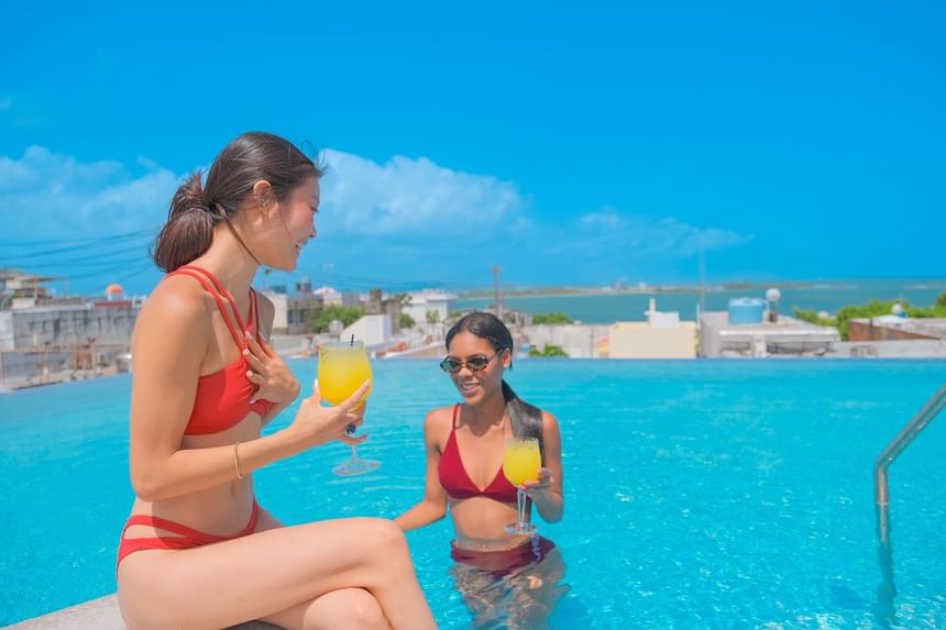 Picture of 2 women in our infinity pool having a conversation and with some cocktails