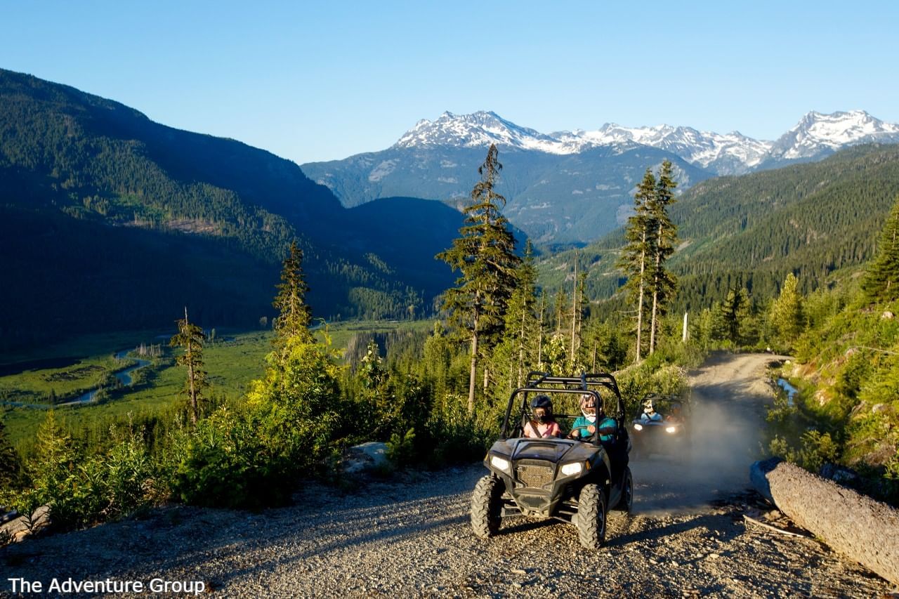 People riding jeeps on a mountain trial with lush greenery near Blackcomb Springs Suites