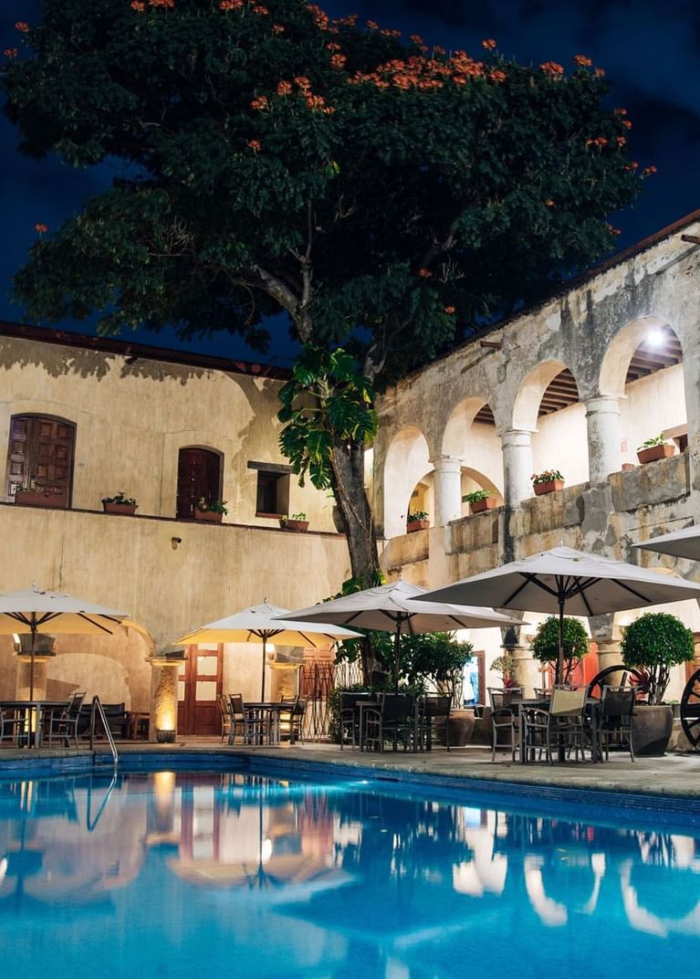Historic courtyard with arched stone architecture surrounds a rectangular pool at Alberca Salon in Quinta Real Oaxaca