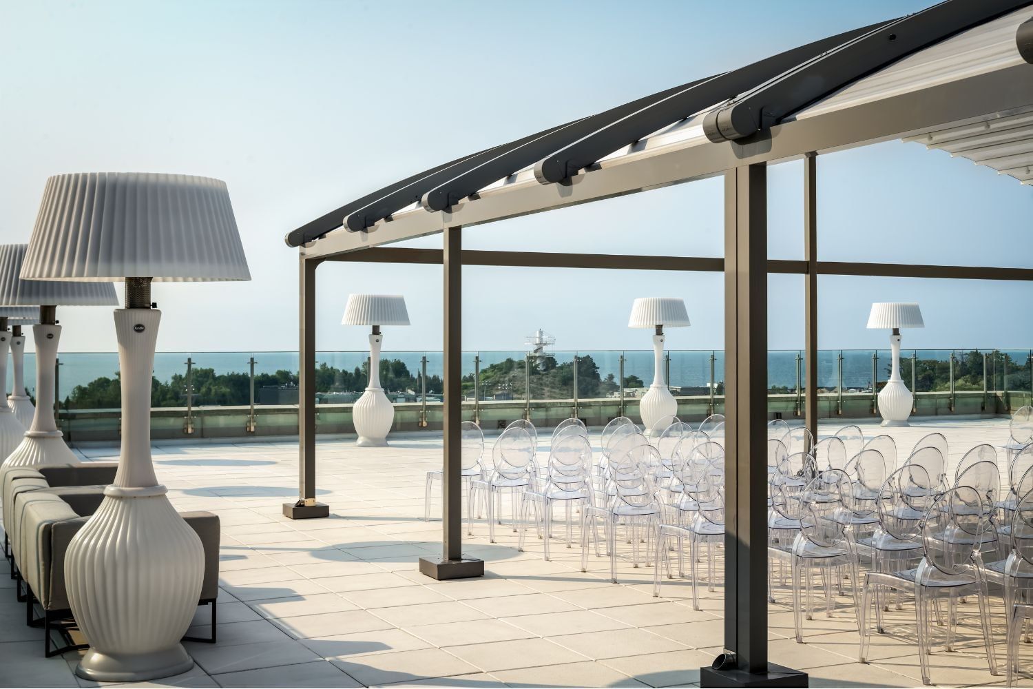 High Park Terrace with clear chairs beneath a modern canopy & oversized white lamps overlooking the water at Hotel X Toronto