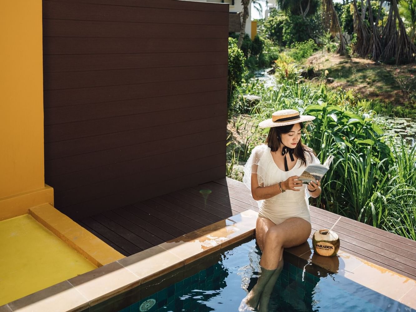A woman is chilling and reading a book while sitting in the plunge pool in the Premium Garden Villa in Phuket Romantic Resort