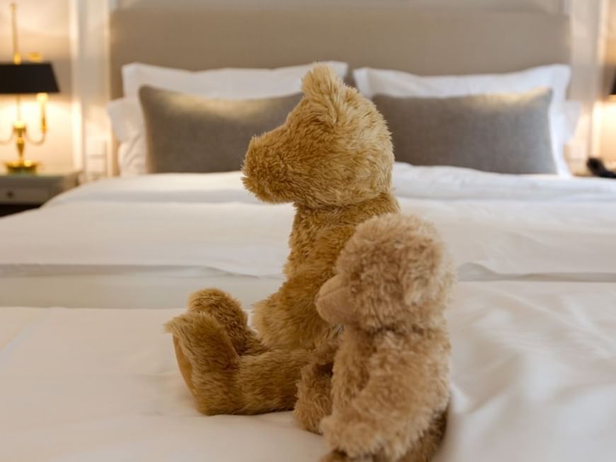 Close-up of teddy bears placed on a bed at Hotel Palace Munich