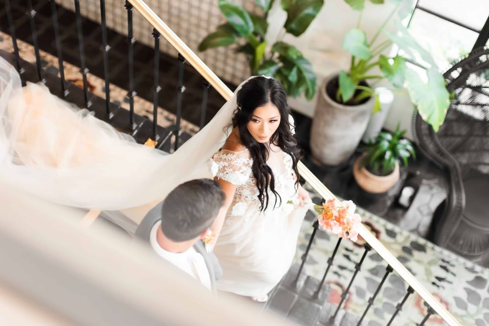Stunning bride and groom ascending a staircase for their wedding at El Prado Hotel