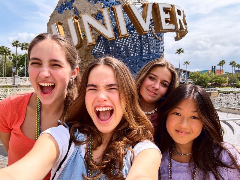 A  group of four women taking a selfie in front of the blue Universal spinning globe in Orlando.