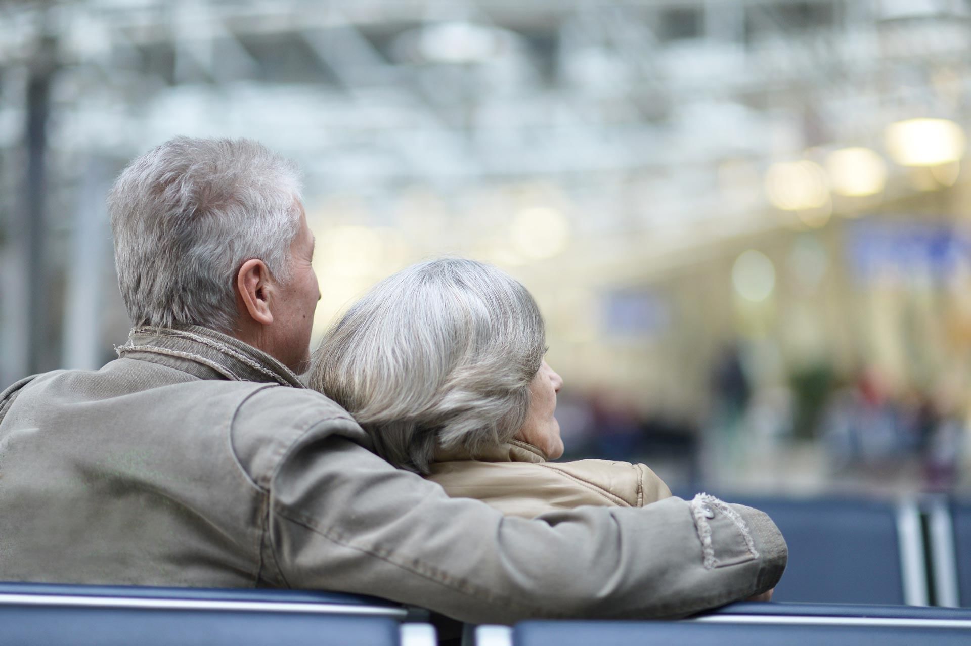 Senior couple sitting on a bench, looking away from the camera