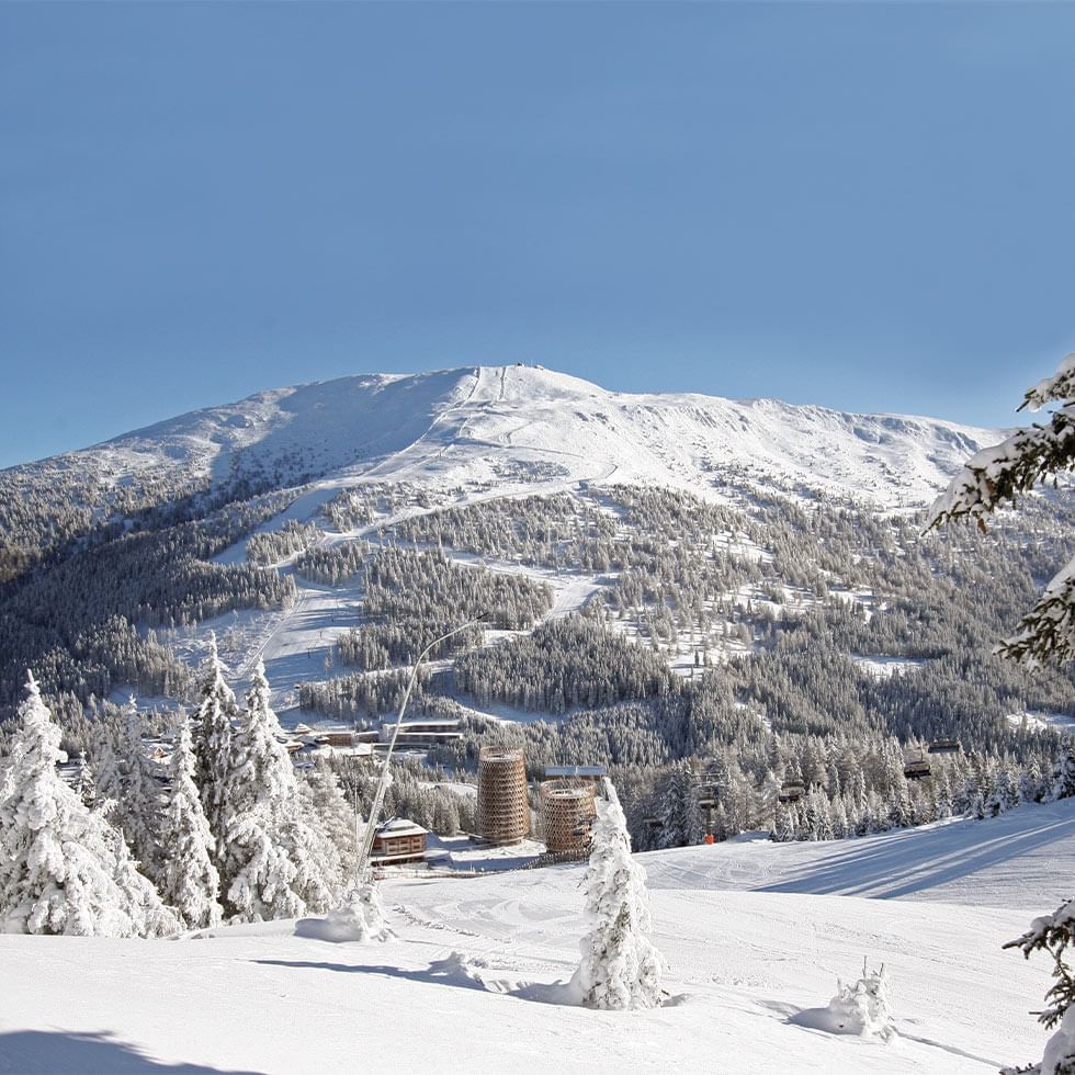 Snow-covered Falkensteiner Hotel Cristallo with trees and mountain