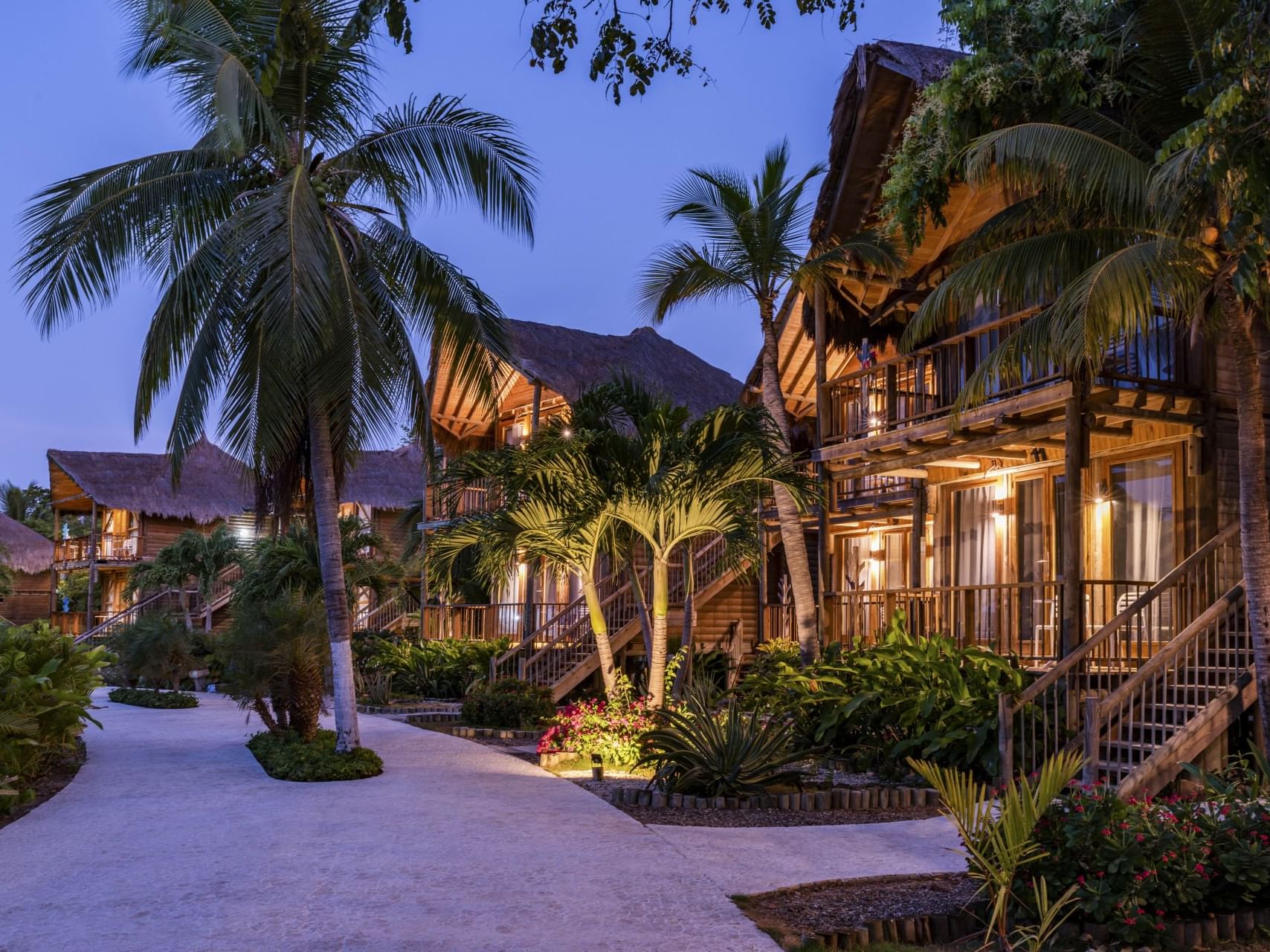 Sunset at a resort with palm trees and a lit walkway at Hotel Isla Del Encanto