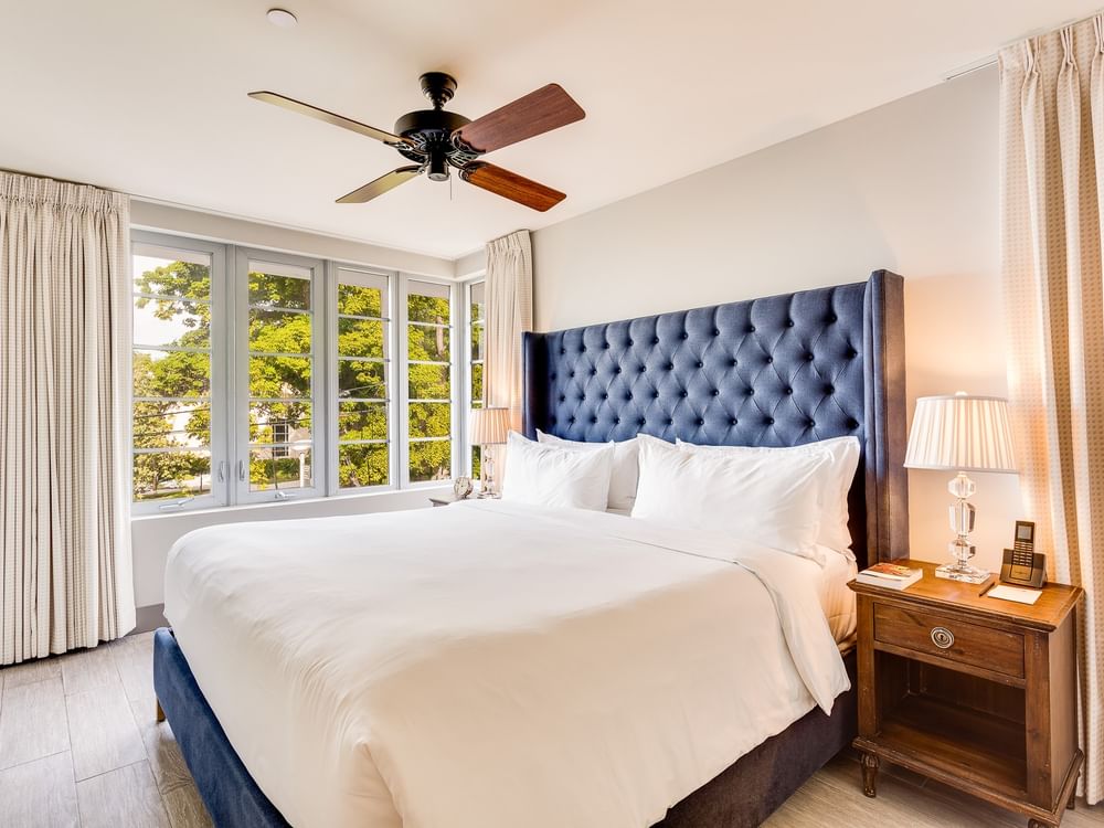 A hotel room with a large bed, blue headboard, and wooden nightstand.