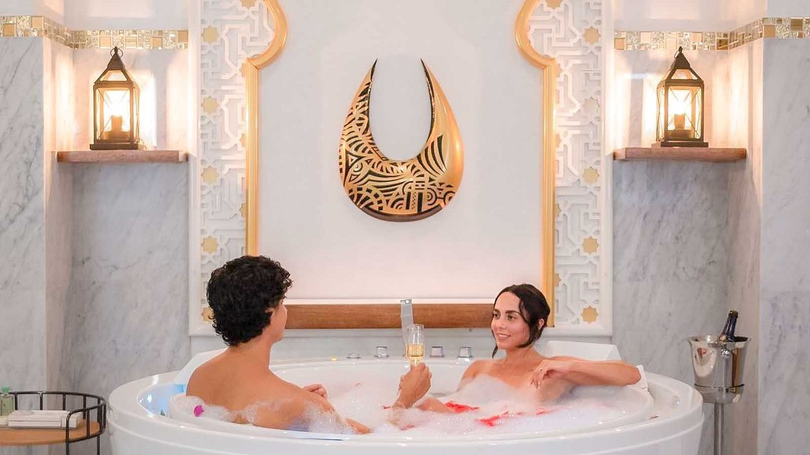 Couple toasting champagne on a tub at The Signature Collection