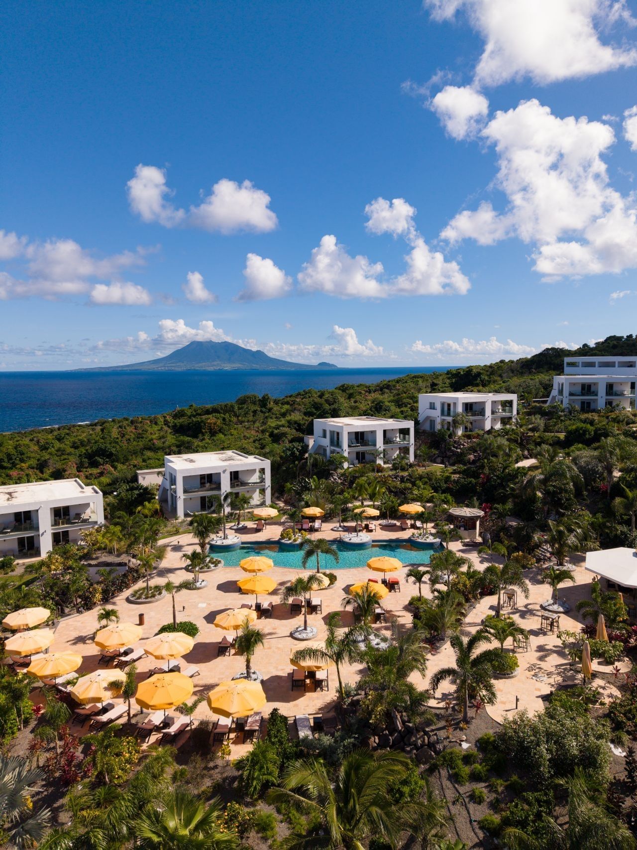 Aerial view of resort guest villas and outdoor pool deck overlooking the vast blue ocean waters at Golden Rock Resort