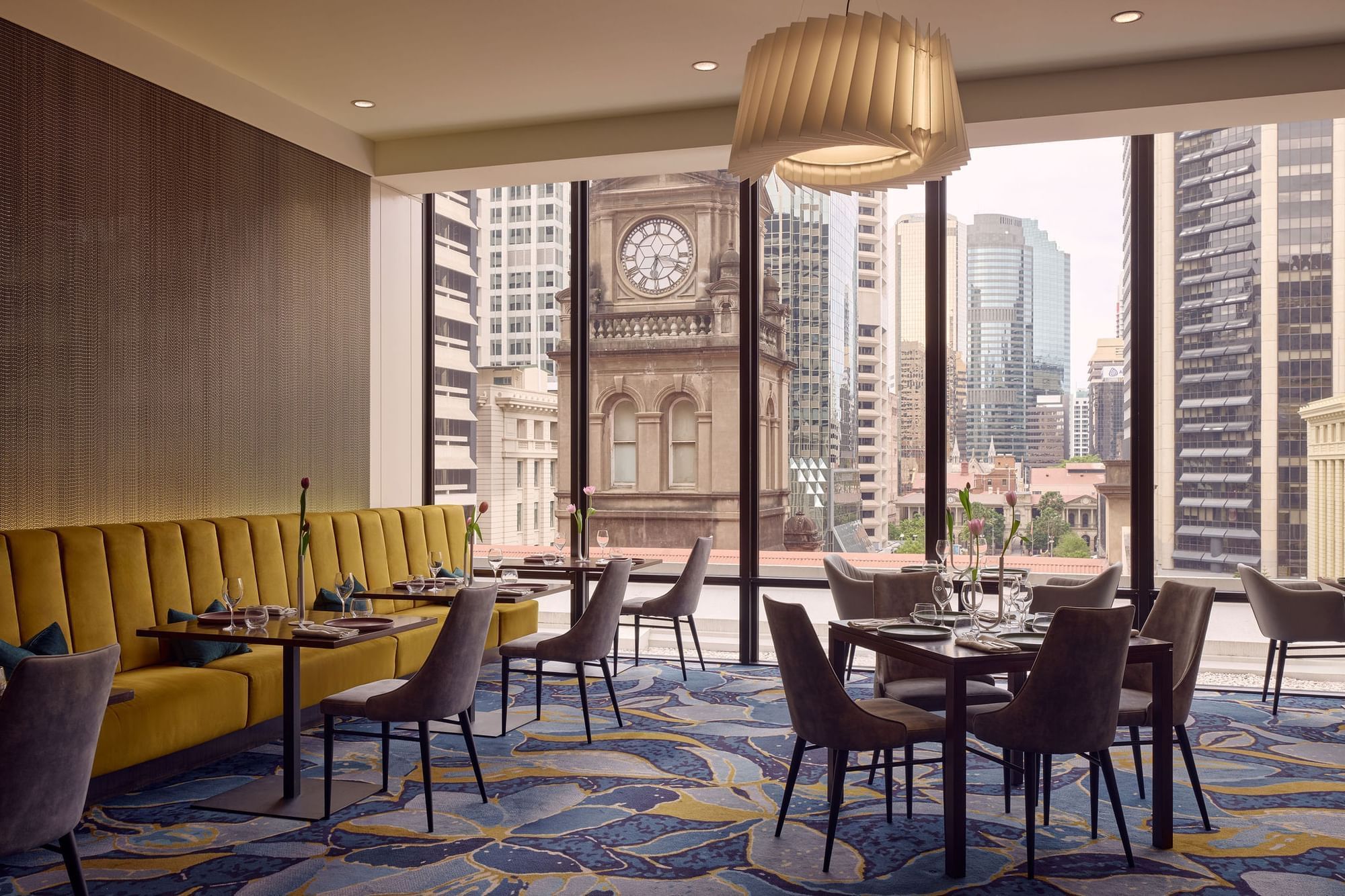 Elegant restaurant interior with city view and yellow seating at Sofitel Brisbane Central