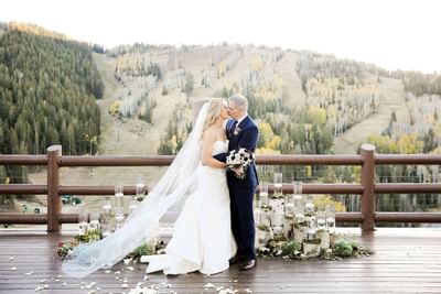 A bride and groom kissing on a deck at Stein Eriksen Lodge