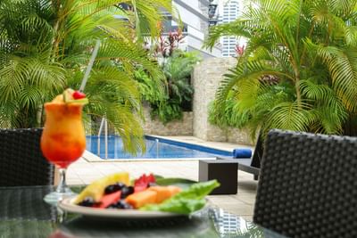 dining table, near pool, with food and cocktail