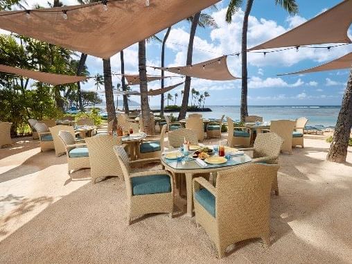 Dining tables arranged outdoors in Seaside Grill near Waikiki Resort Hotel by Sono