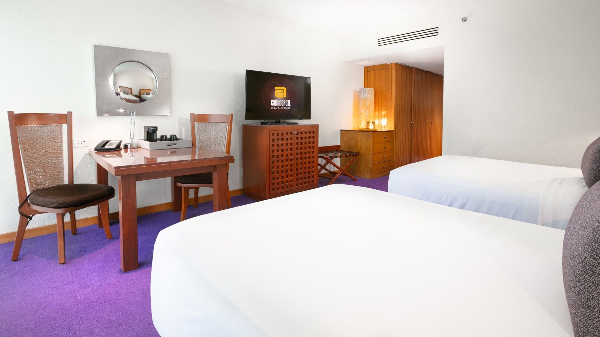 2 Double Deluxe room featuring a wooden desk, two beds, and purple floor accents at Camino Real Polanco Mexico
