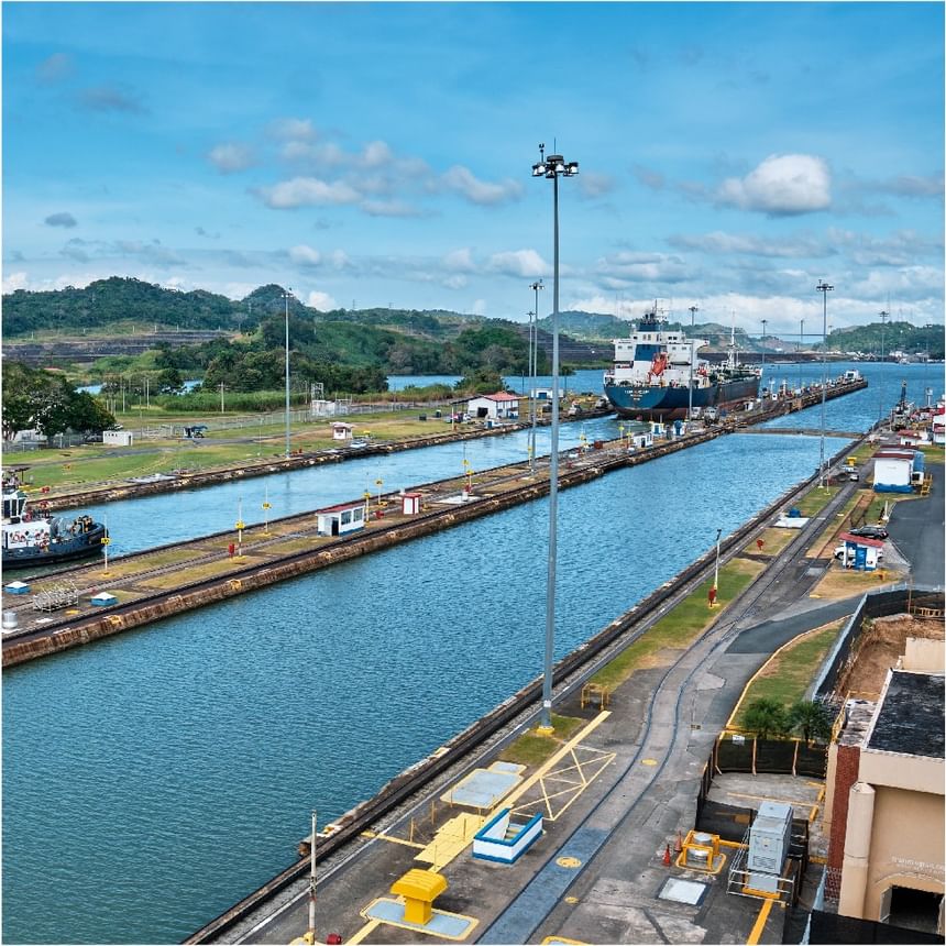 Esclusas del canal con carguero y remolcador bajo un cielo nublado cerca de Megapolis Hotel Panama