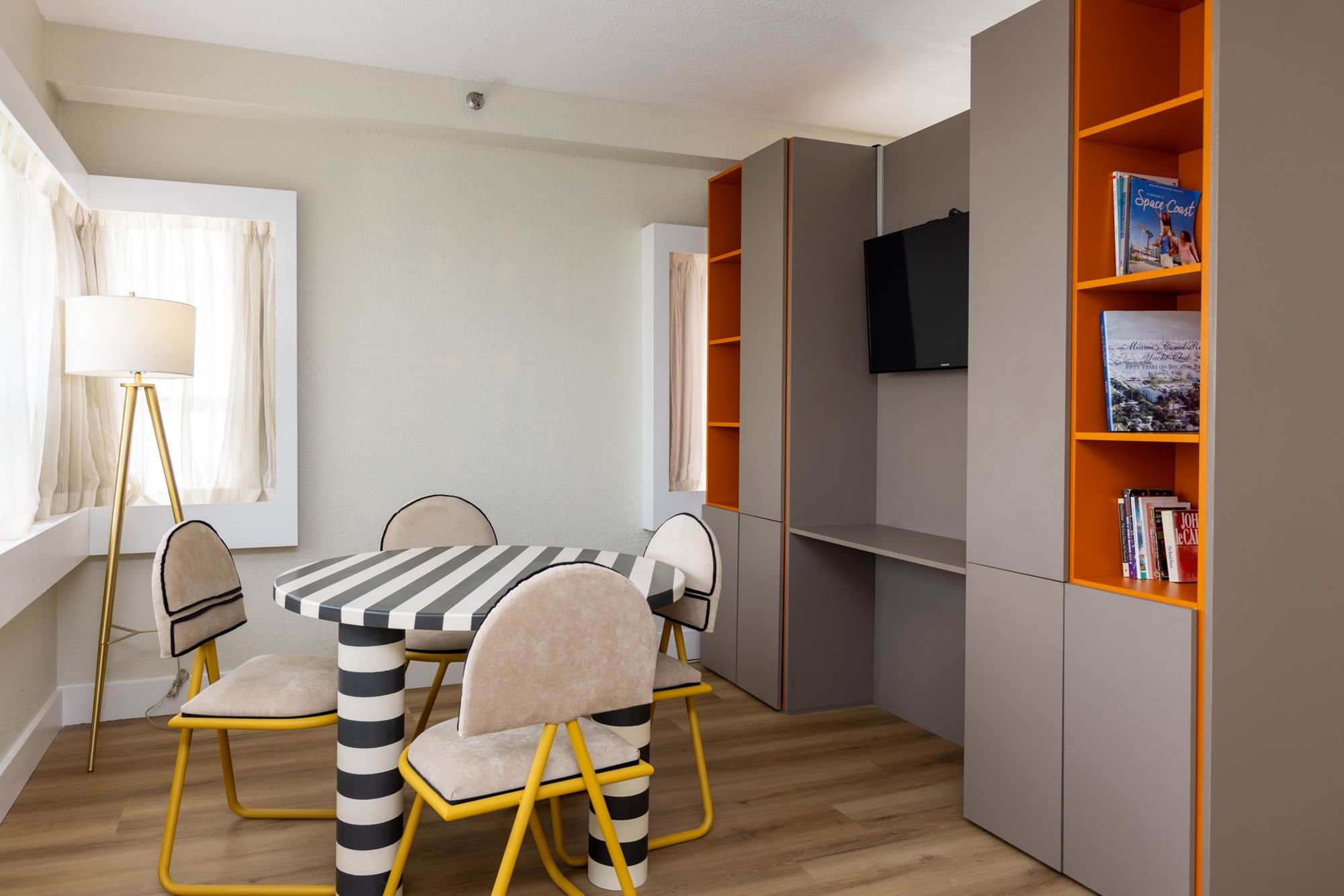A studio room with a dining table, chairs, TV, and bookshelf