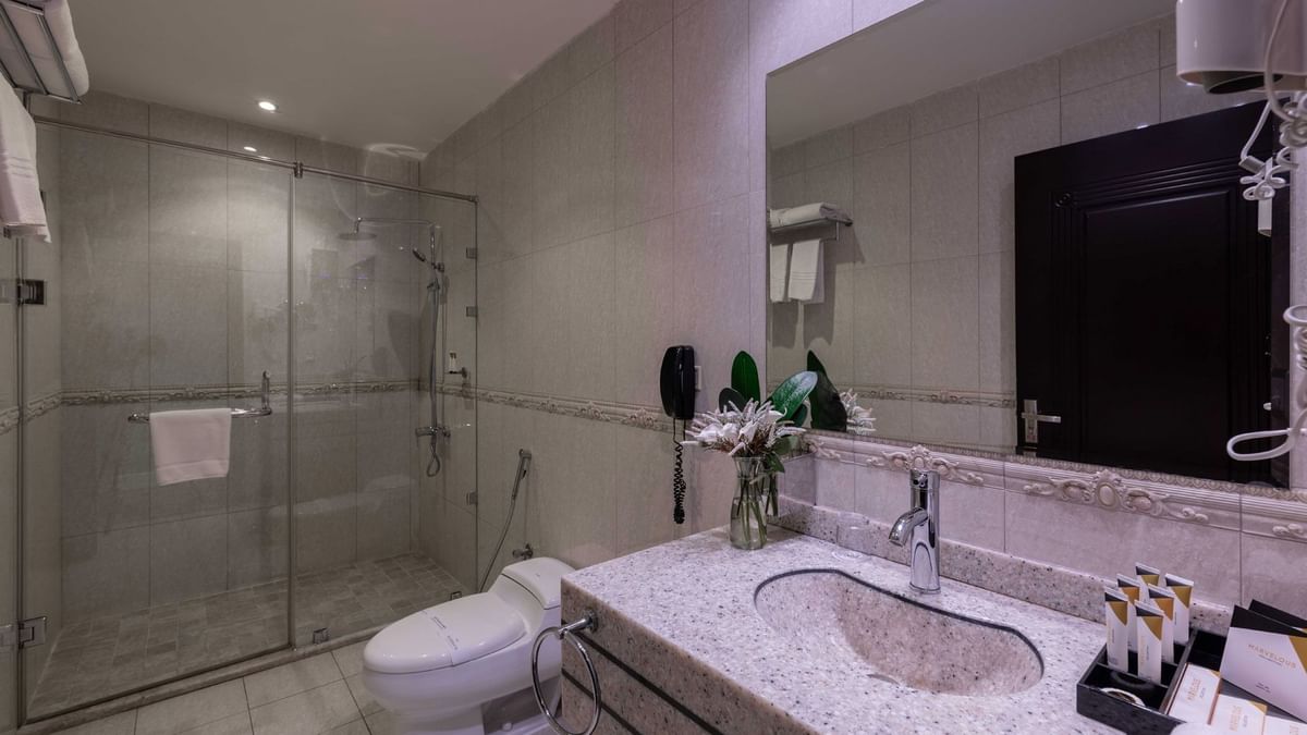 Bathroom with a granite vanity by a glass shower and white toilet in Deluxe Room City View at Warwick Al Jubail