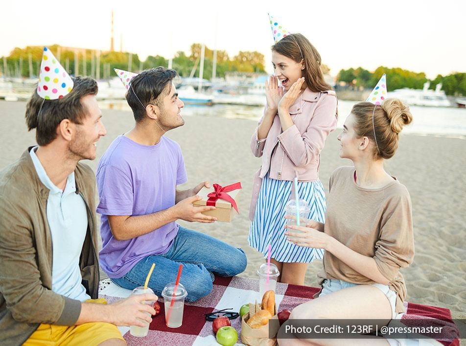 Group of friends gifting a present for a beach birthday party 