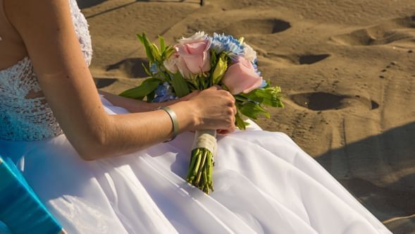 A bride holding a bouquet by the beach at Hotel Villa Varadero