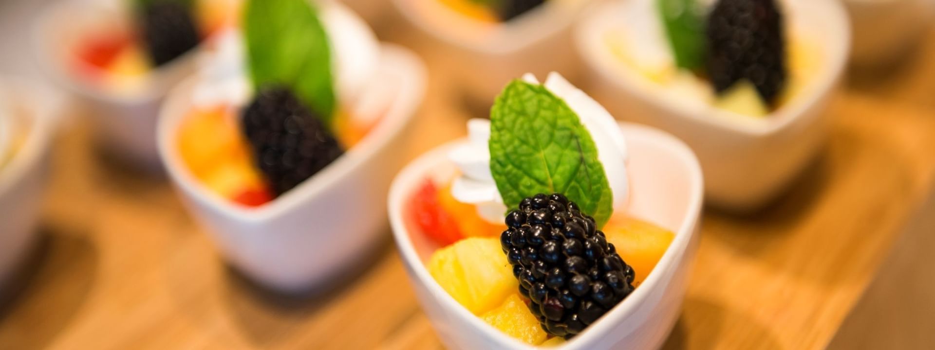 Fruit cups with blackberries under mint leaves surrounding a wooden board in Verandah at Warwick Paradise Island Bahamas