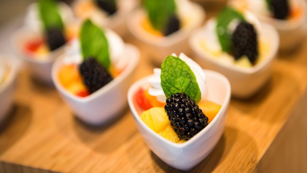 Fruit cups with blackberries under mint leaves surrounding a wooden board in Verandah at Warwick Paradise Island Bahamas