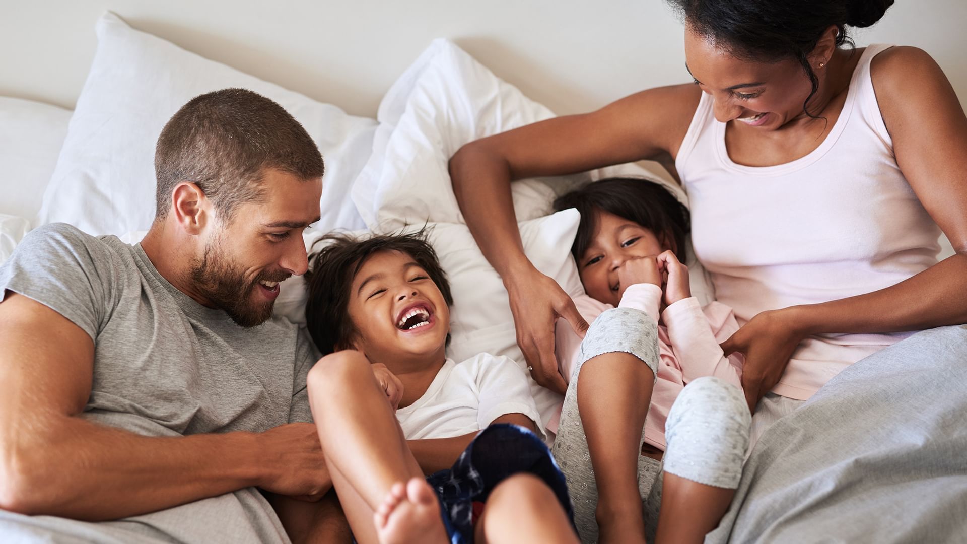 A happy family of four lying on a bed together.
