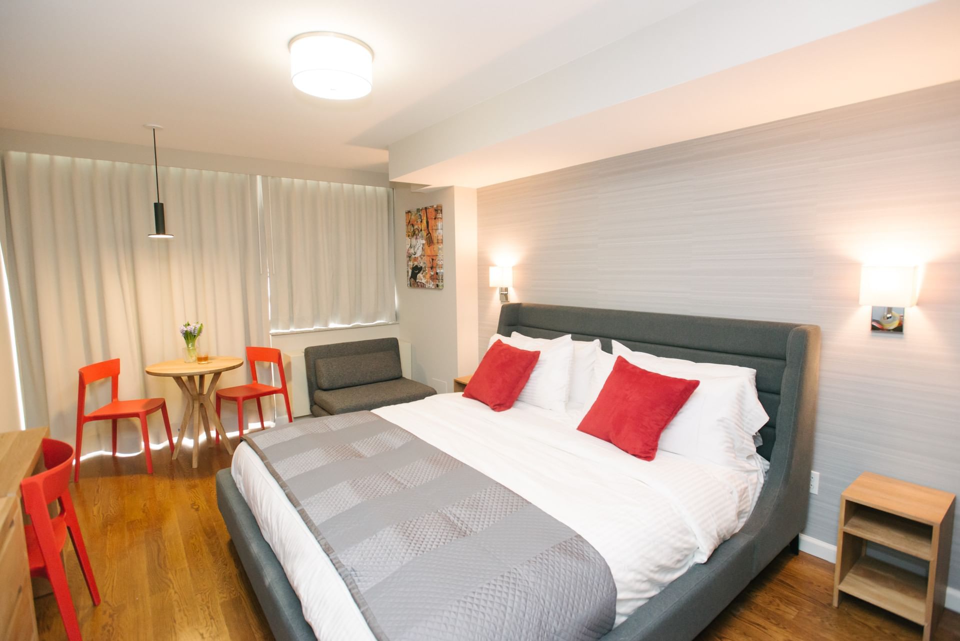 A hotel room with a king bed, dresser, table and chairs, sofa, and wood floor