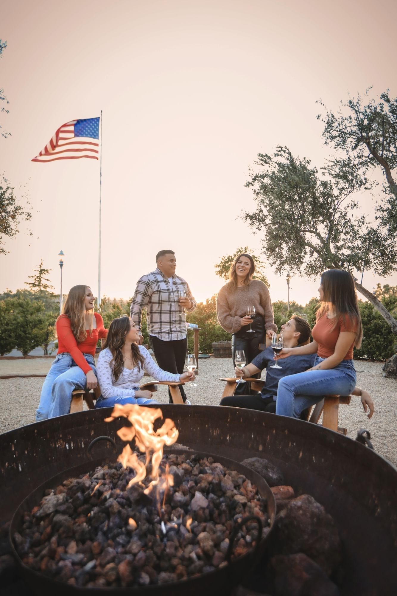 Group of six people gathered around a firepit facing each other