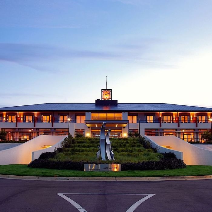 Mercure Kooindah Waters at dusk with illuminated windows and a landscaped front area