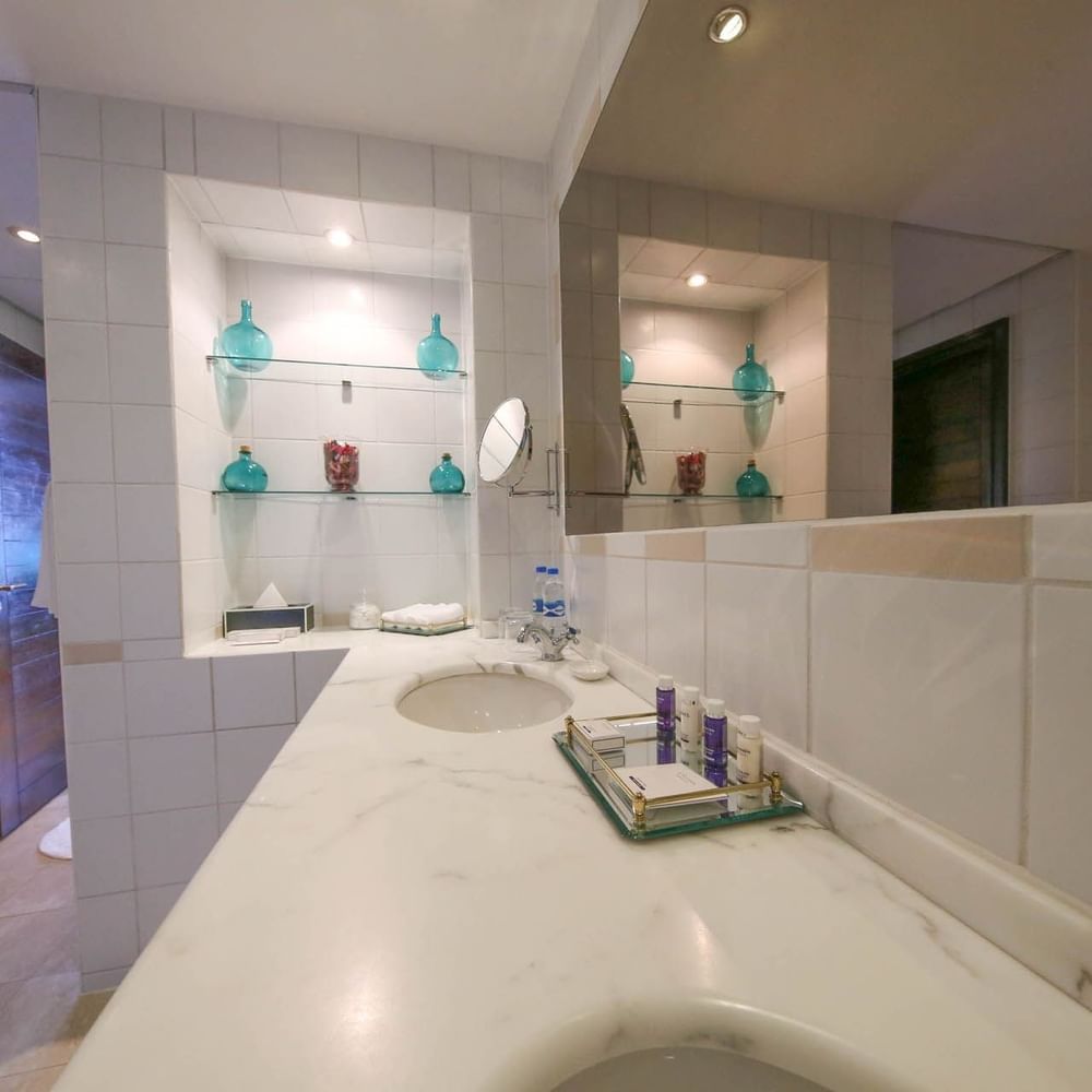 Elegant bathroom with a large vanity and glass-encased toiletries at Dar Es Salaam Serena Hotel Dar es Salaam.