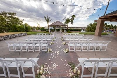 Outdoor wedding ceremony setup with white chairs, rose petal aisle, and waterfront gazebo at London Bridge Resort