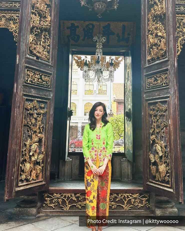 A woman dressed in Nyonya Kebaya stood in front of the door of the Pinang Peranakan Mansion - Lexis Suites Penang