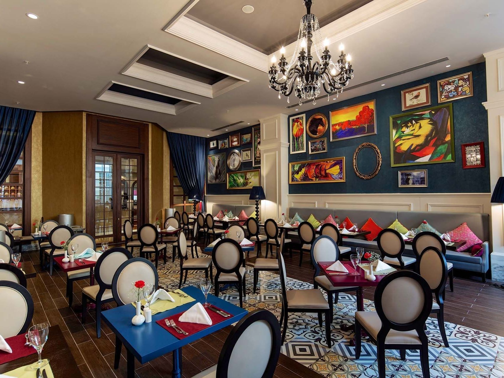 Dining area with patterned floor, chandelier, and colorful artwork on the wall at Titanic Deluxe Golf Belek