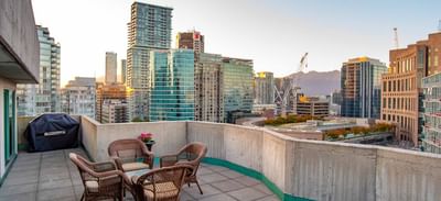 Rooftop patio with wicker furniture & downtown skyline view at Rosedale on Robson, one of the best hotels in Vancouver