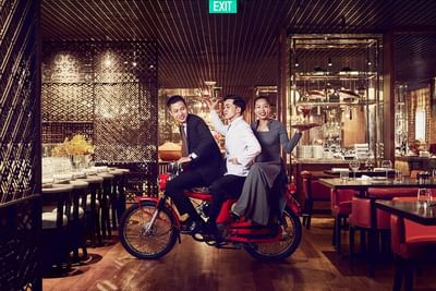 Square One interior with three elegantly dressed individuals posing on a red bicycle at Park Hyatt Saigon
