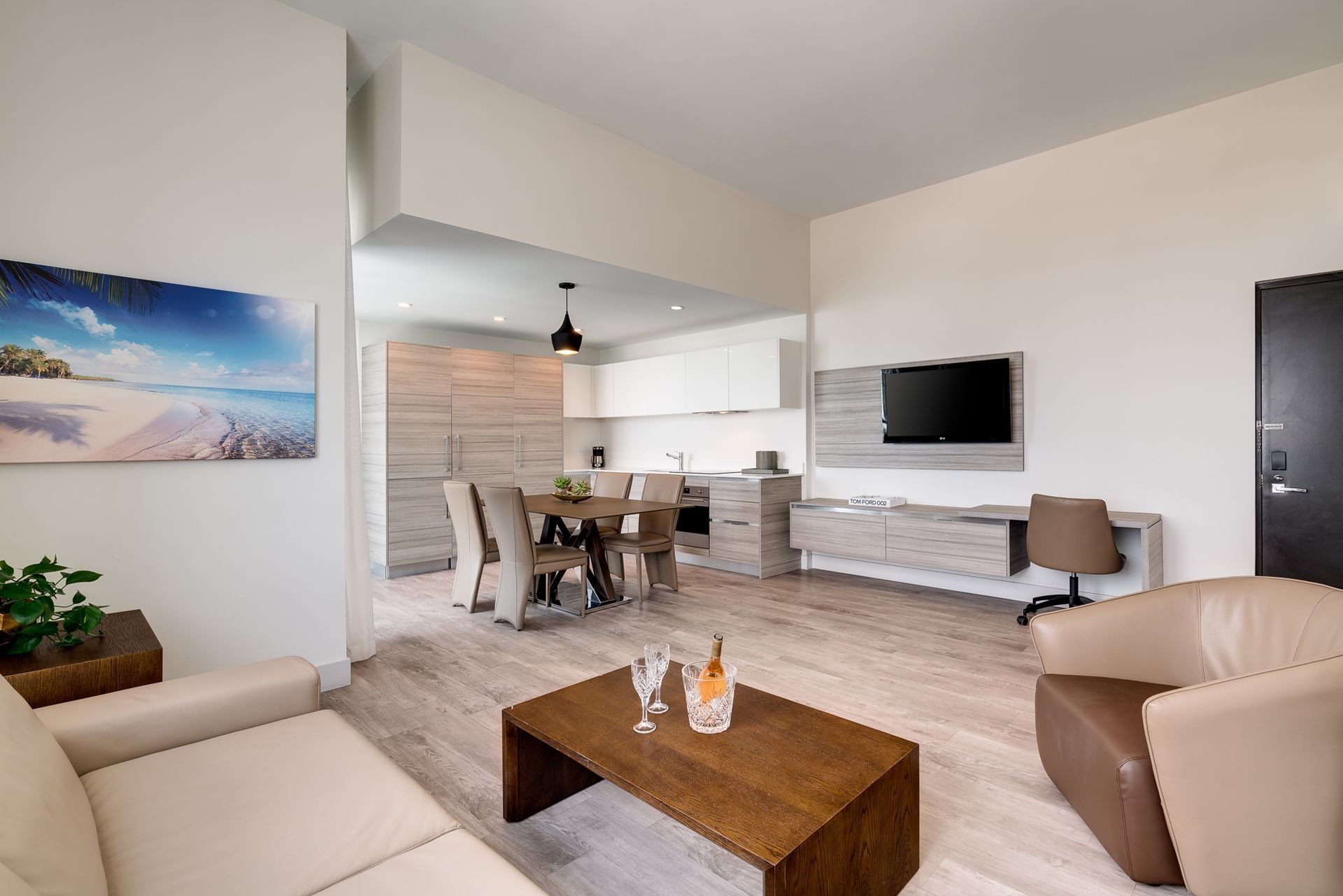 A modern living room and kitchen area with a dining table, TV, and comfortable seating.