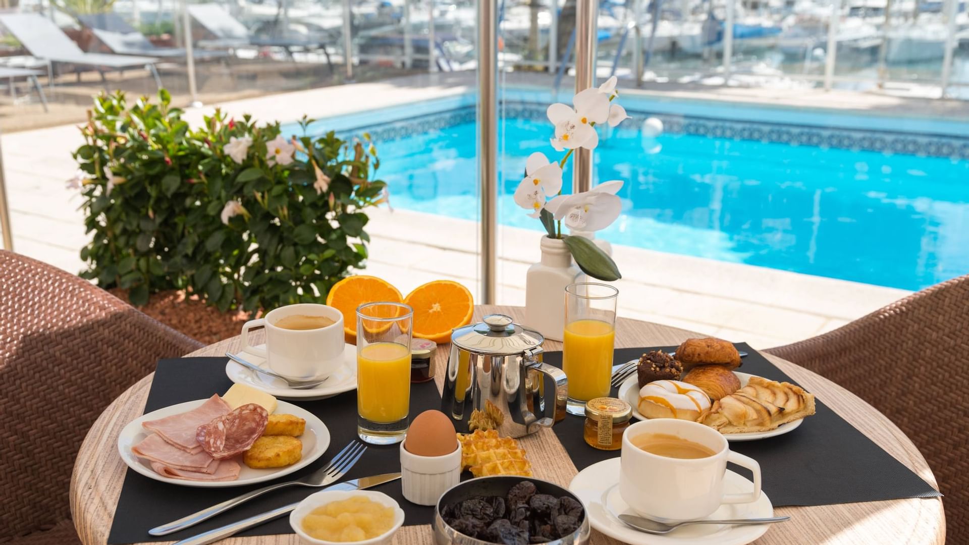Breakfast on a table by an Outdoor Pool at Originals Hotels