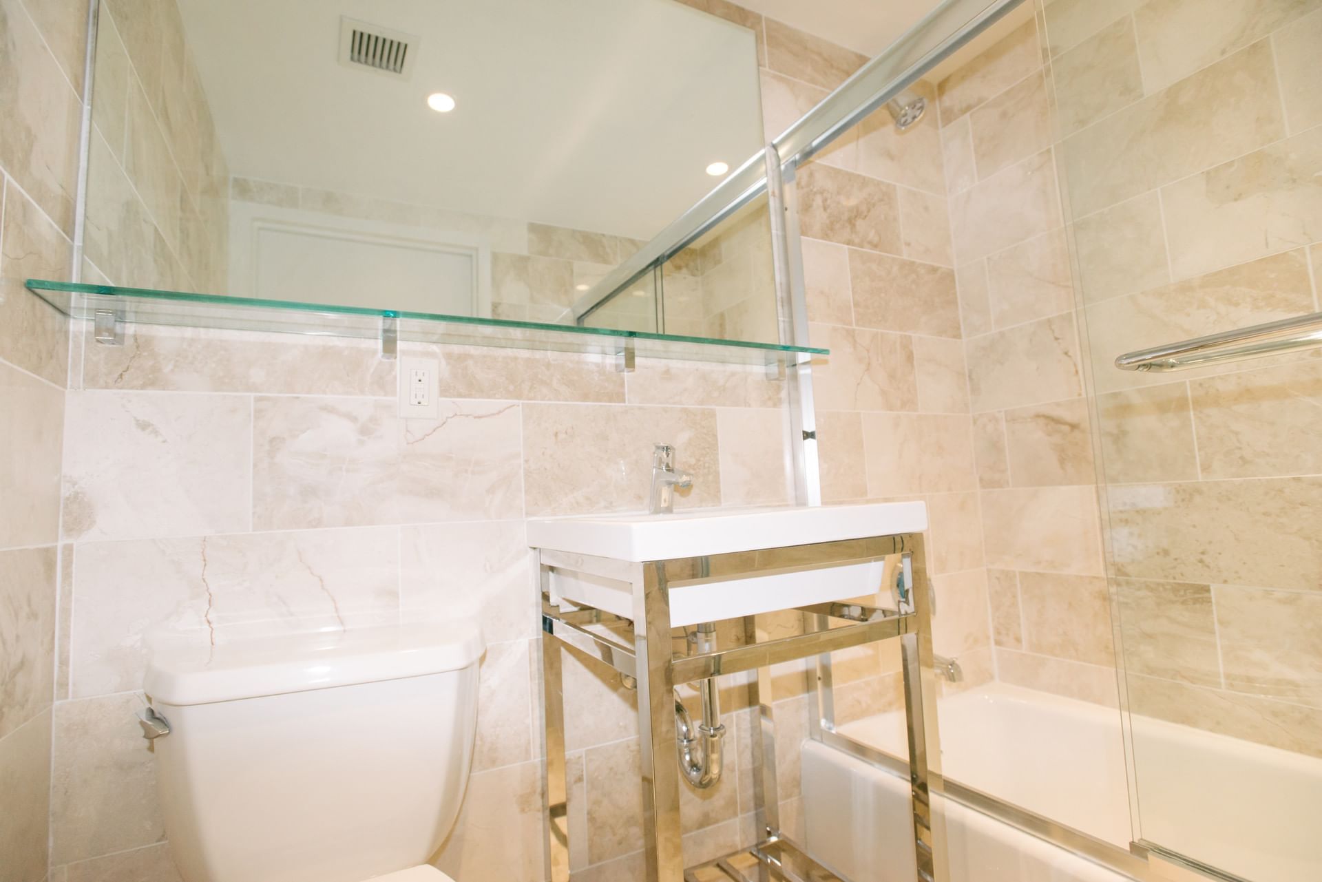 A bathroom with a toilet, sink, bathtub, and mirror.