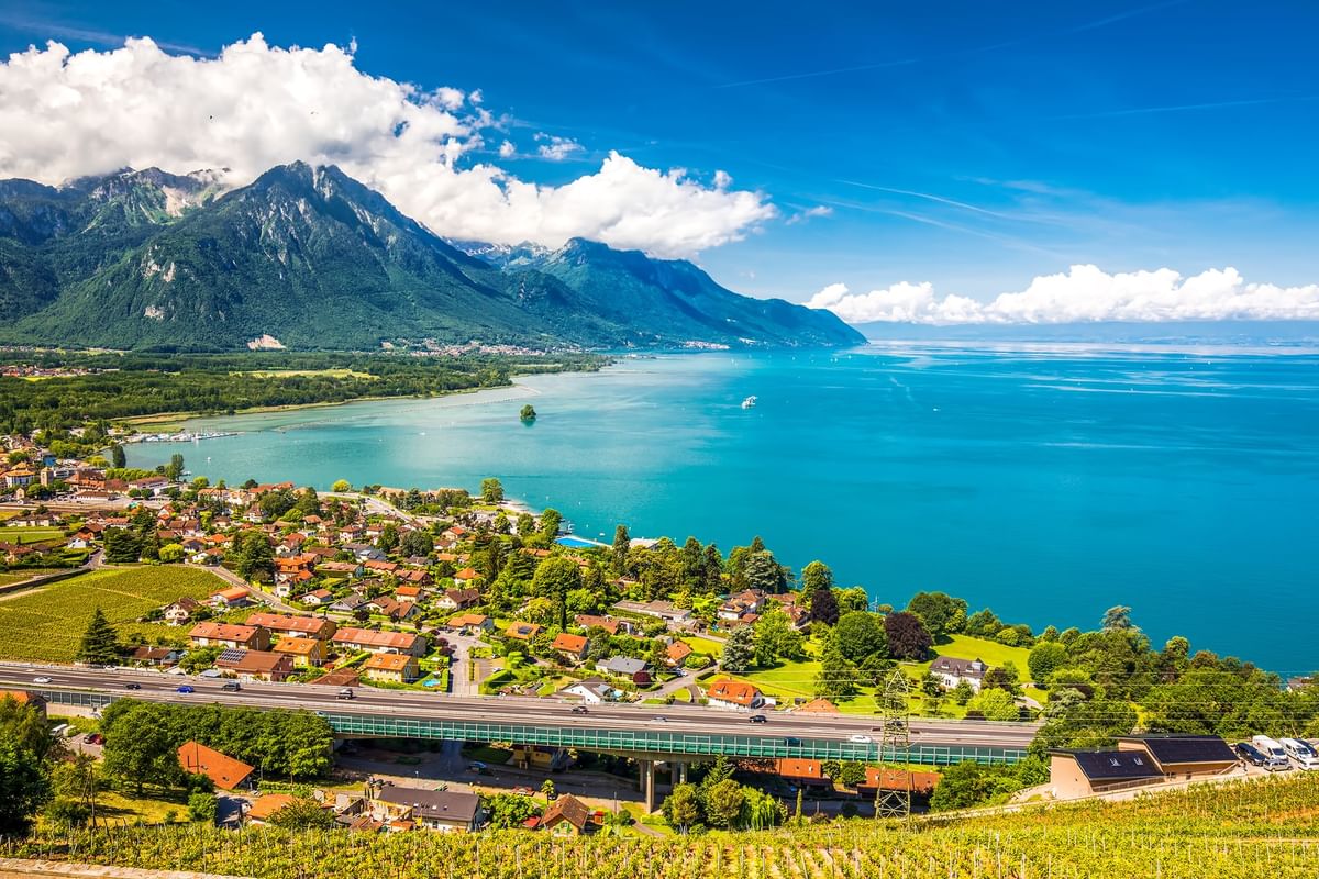 Aerial view of a coastal town by a mountain under white clouds near Warwick Geneva