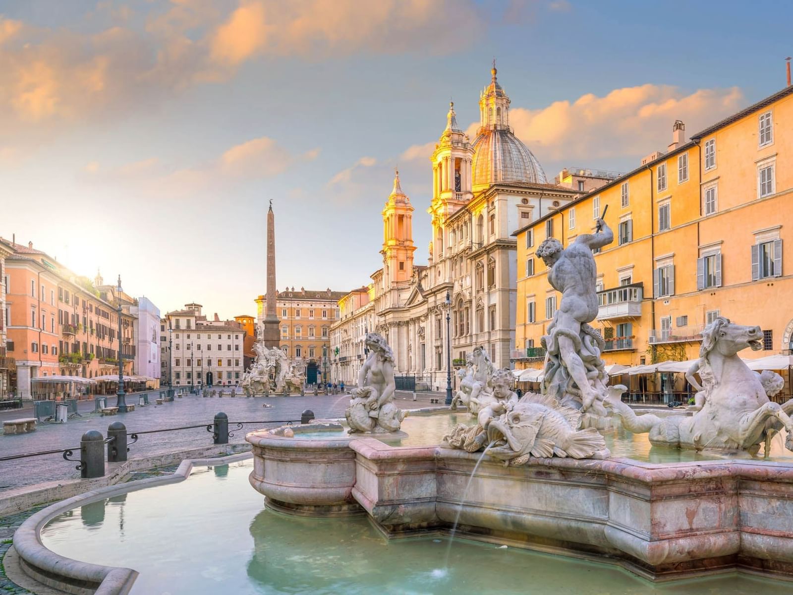 Scenic view of Piazza Navona at dawn with glowing statues and fountain in soft sunrise light near The Guardian Hotel