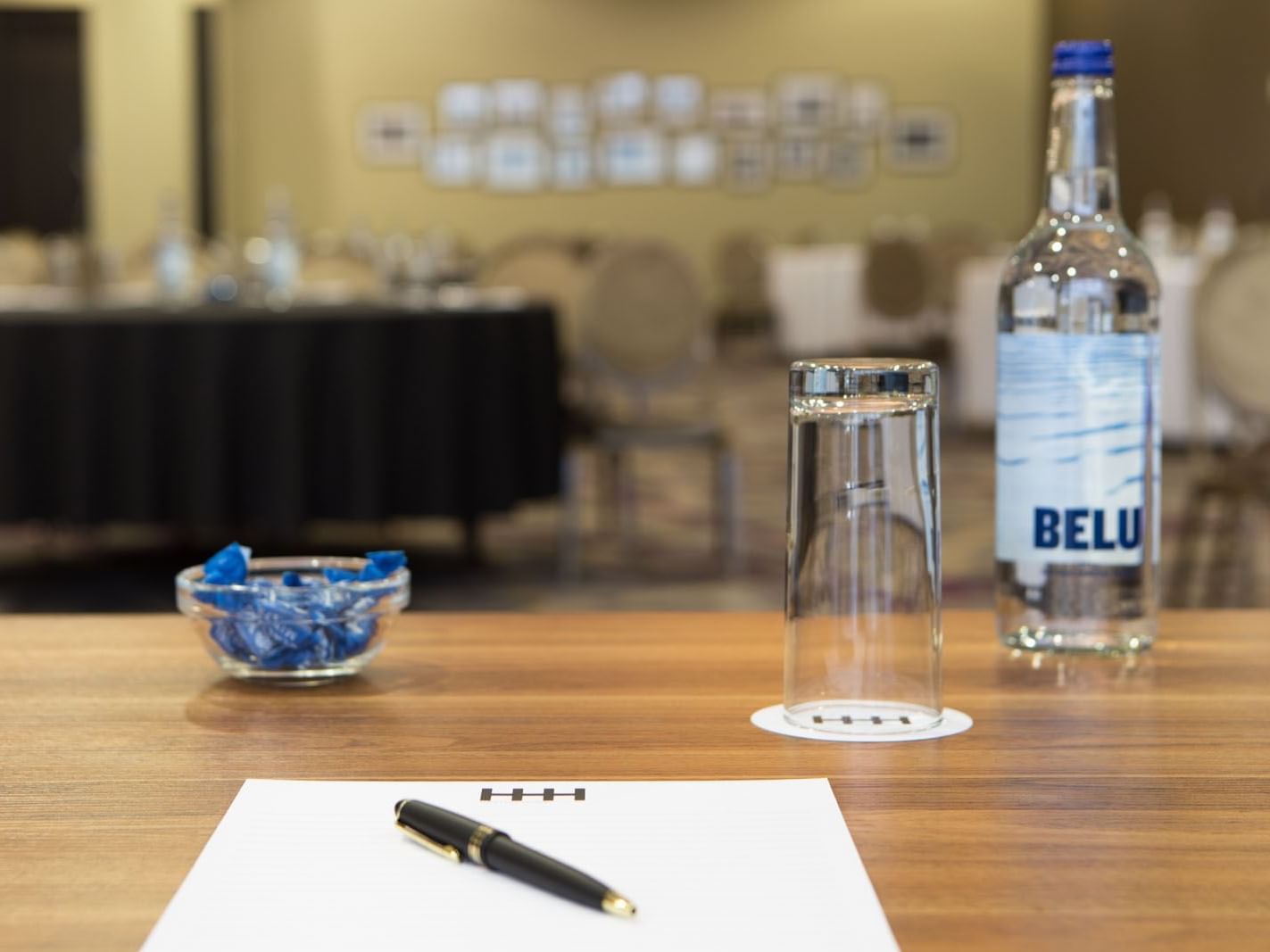 Well-organized conference table with a notepad, Belu water bottle, and candies at Heston Hyde Hotel