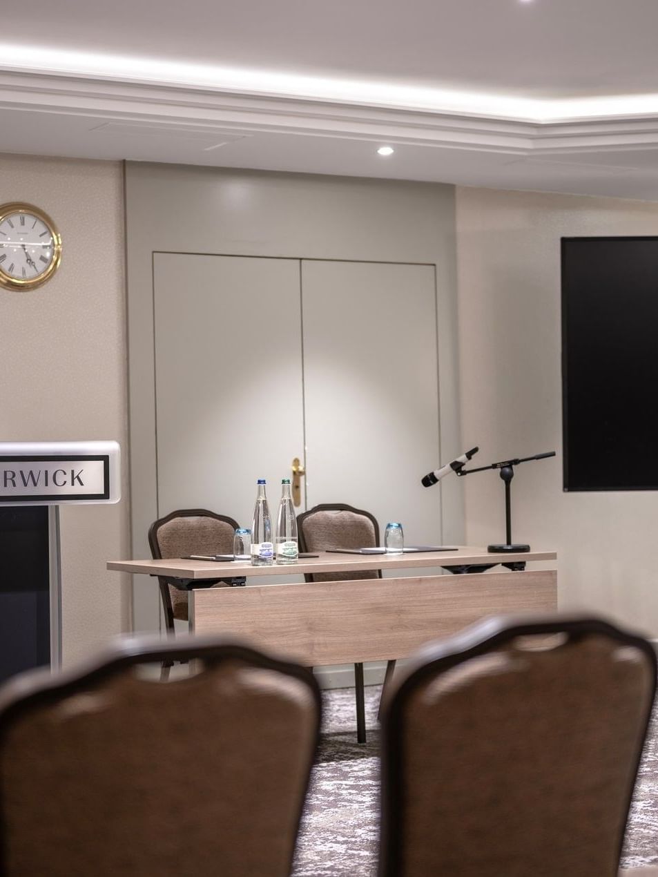 Podium and speaker table by a large screen under soft ceiling lights in Mont-Rose at Warwick Geneva