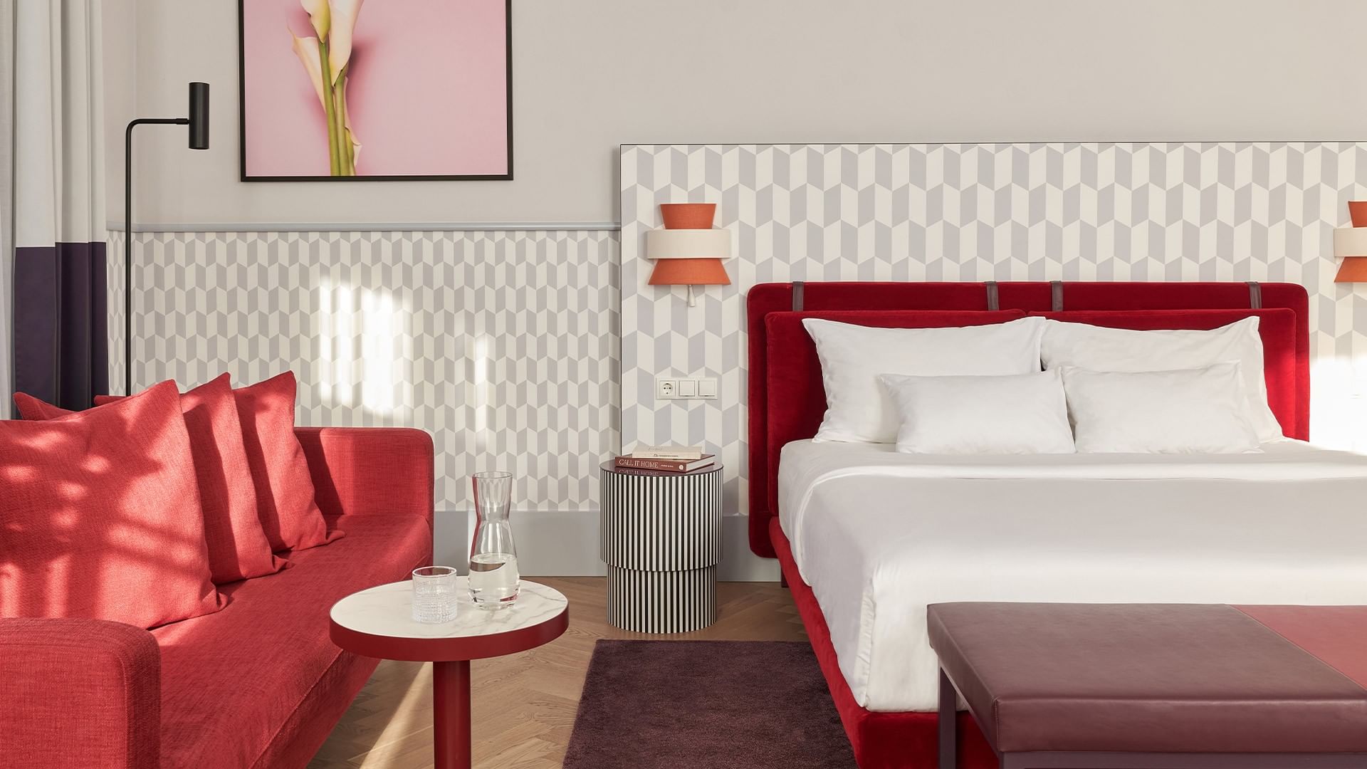 Elegantní Junior Suite s červenou postelí a pohovkou v Falkensteiner Hotel Prague.