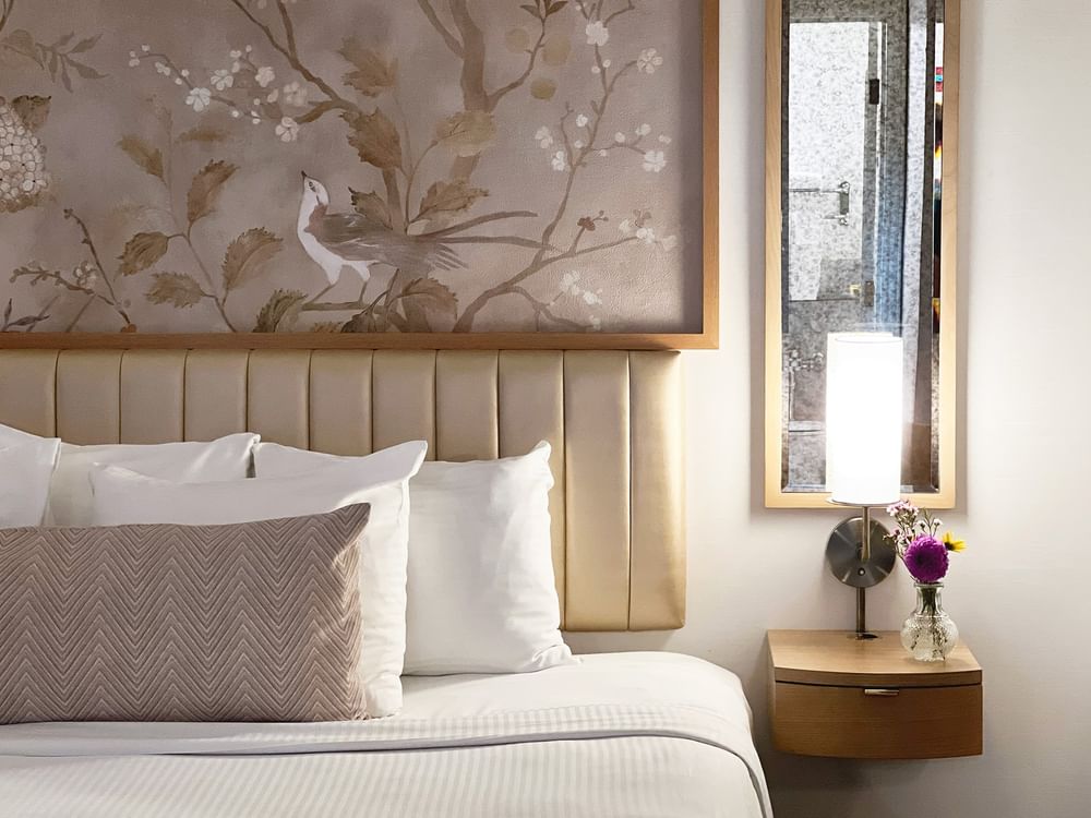 Close-up of bed with pillows by side table in Accessible King Room at Warwick Allerton Chicago