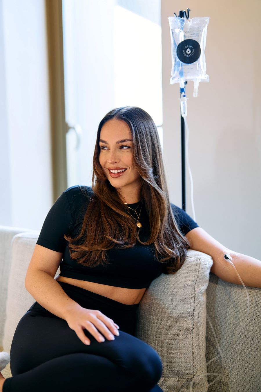 Woman sitting on couch receiving IV treatment at The Londoner