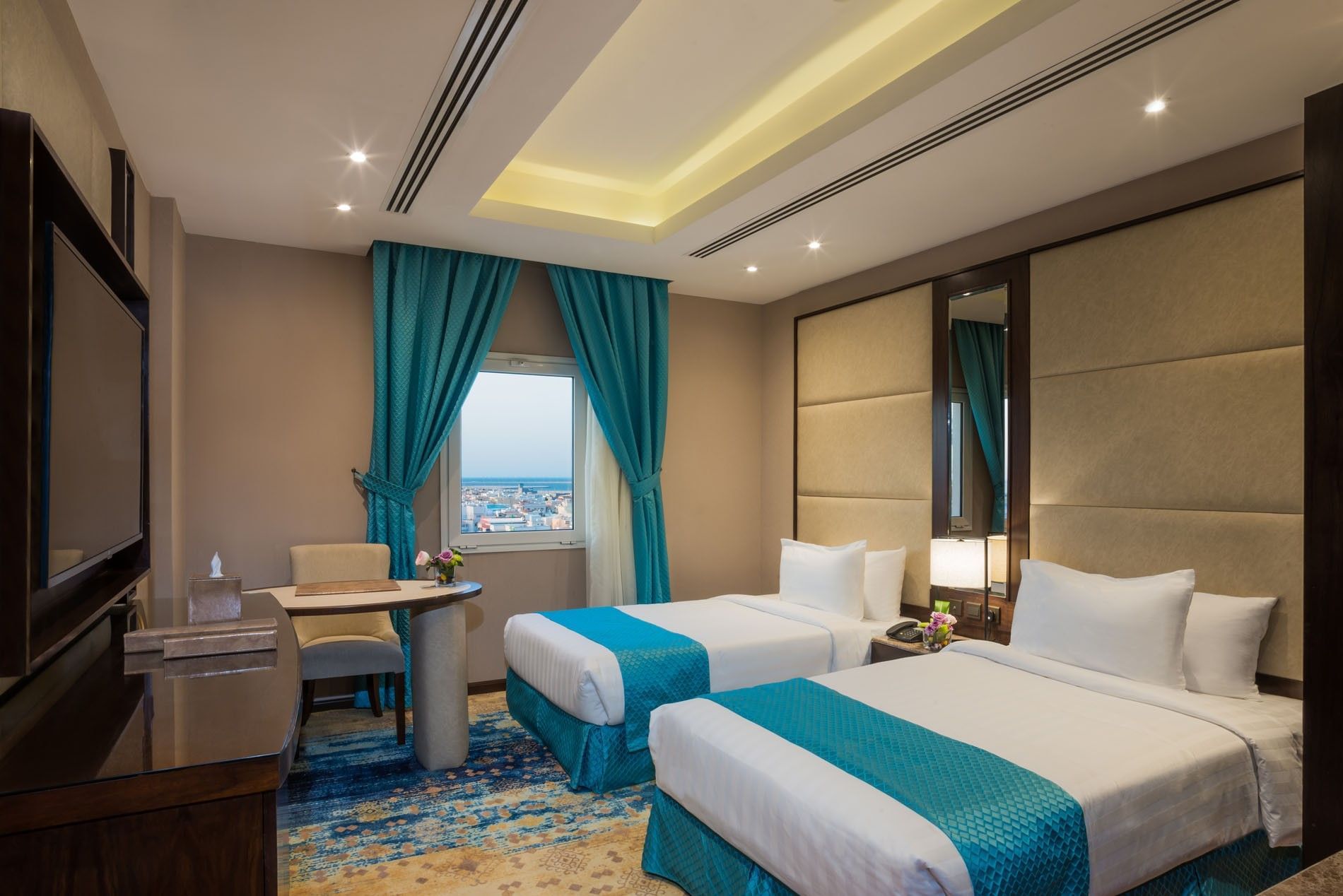 Two beds with a work desk by the window in Family suite at Naviti By Warwick Dammam