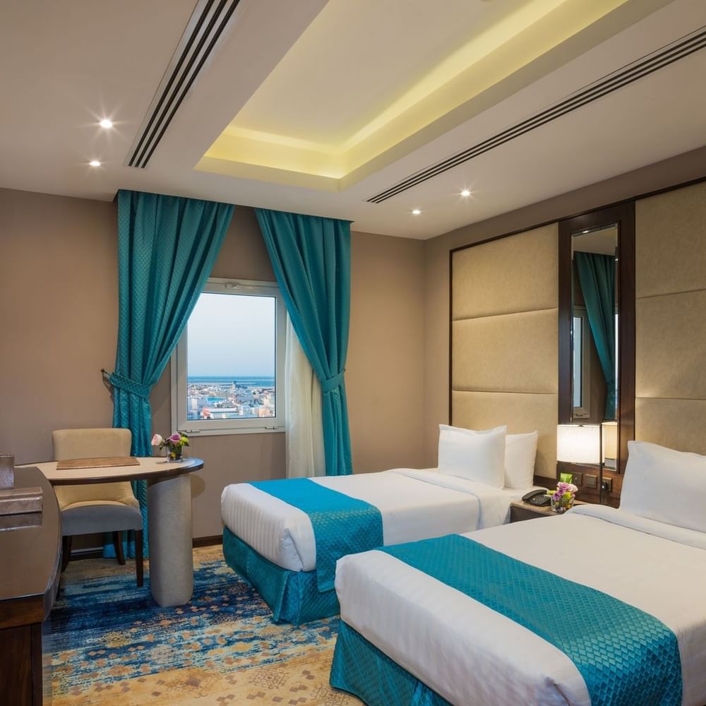 Two beds with a work desk by the window in Family suite at Naviti By Warwick Dammam