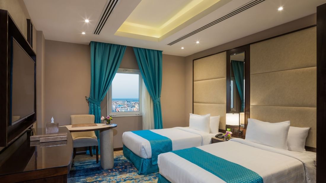 Two beds with a work desk by the window in Family suite at Naviti By Warwick Dammam