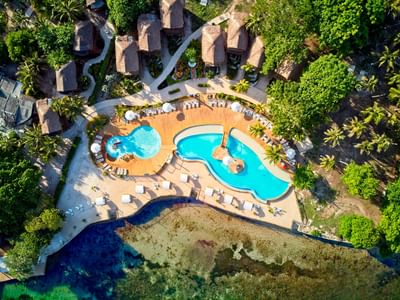 Ariel top view of Hotel Isla Del Encanto with palm trees, pool, and ocean view